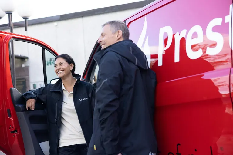 To Presto-medarbejdere ved en rød servicebil