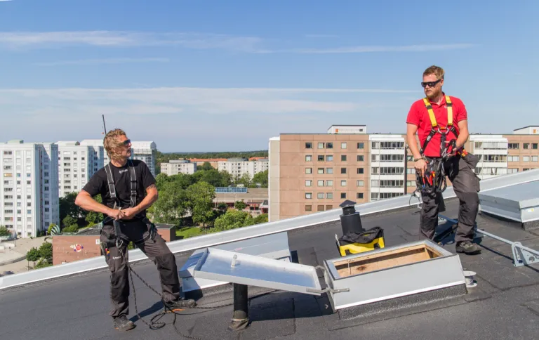 To teknikere ved en åben røgventilationslem på et tag